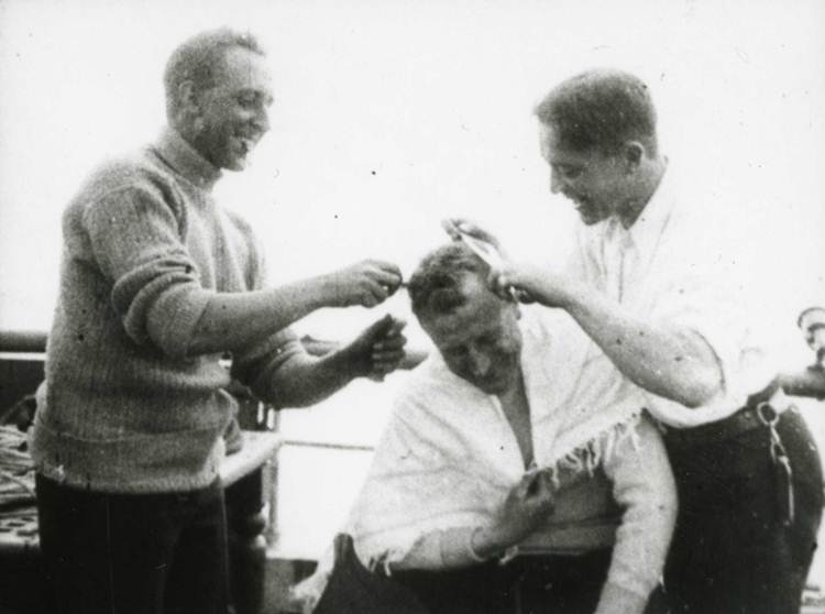 One man cutting another’s hair on board [steam yacht] Terra Nova No. 3 (catalogue reference: COPY 1/562/40)