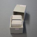 Image of smaller grey box with its lid off, revealing slides housed within