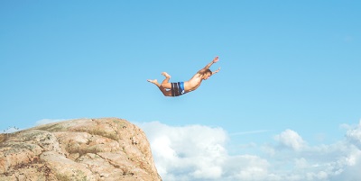 Image of a person diving, with a pale blue sky as the backdrop