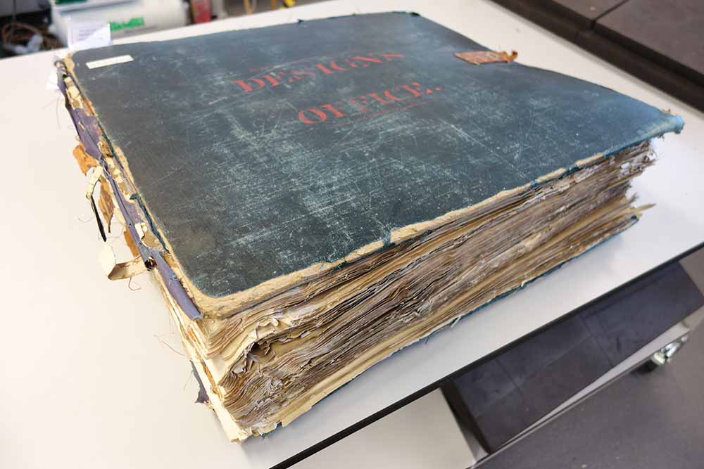 A large volume with blue cover labelled 'Designs Office'. Due to wear the volume's spine is missing and the cover is worn around the edges.