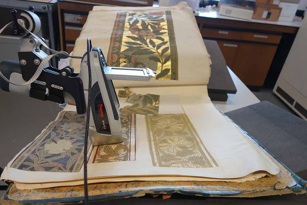 The XRF analyser is positioned above a wallpaper border in preparation for analysis. The large size of the opened volume can be seen.