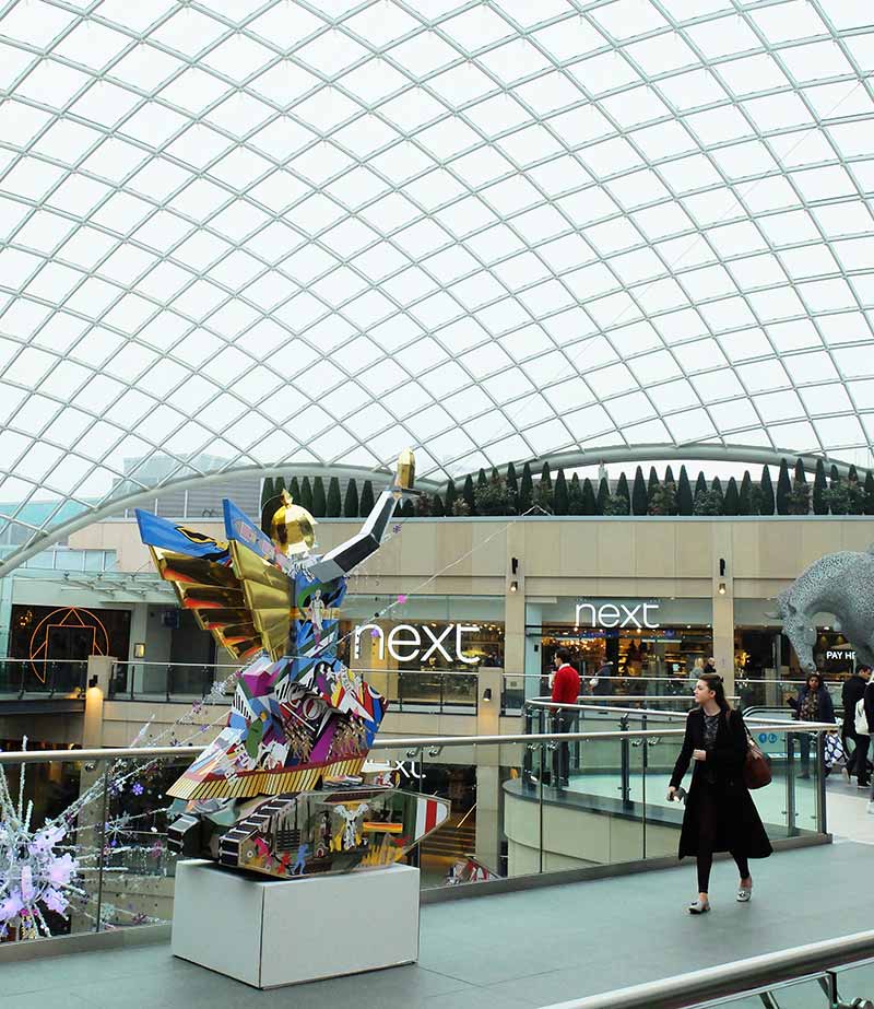 Sculpture of a winged woman standing atop a tank, in a shopping centre