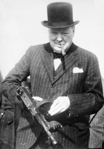 Black and white photograph of Winston Churchill wearing a bowler hat and holding a gun