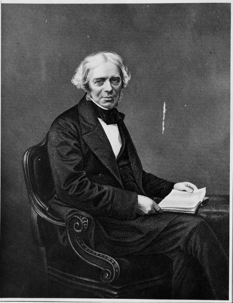 Engraving of Michael Faraday sitting at a table with an open book