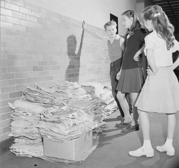  Three school students examine a large pile of newspapers