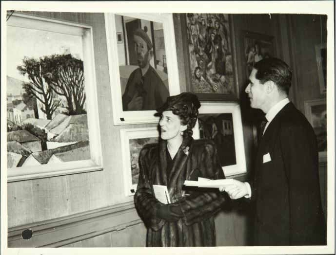 Duchess of Kent and Sousa Leao, Charge d’Affaires of The Brazilian Embassy, at the exhibition, looking at the painting ‘Landscape’ by Quirino da Silva. Document reference: FO 371/37862