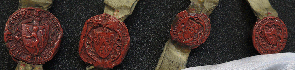 A close up photograph of four small, red wax seals of the recipients of land in a medieval charter of 1359