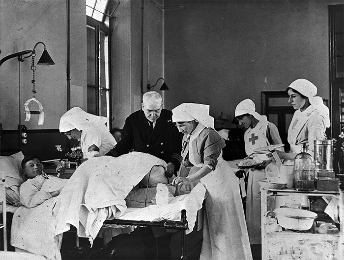A doctor and four nurses treating a wounded soldier in a ward during the First World War.