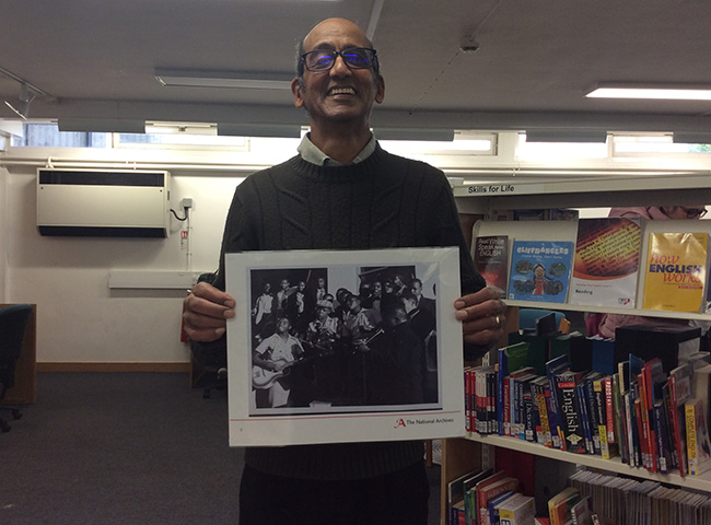 Marcus holding the photographic image of INF 10/54/21 – remembering guitar tuition in the townships.