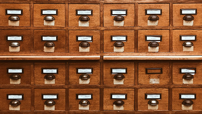 Colour photograph of four rows of six draws in a wooden filing system.