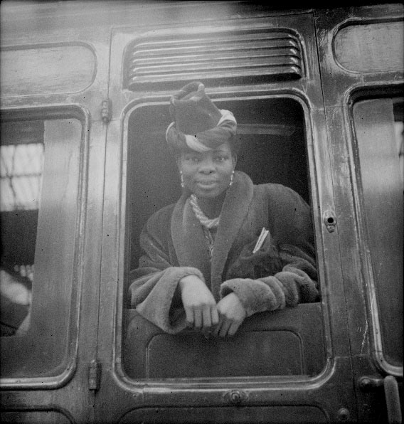 Princess Omo-Oba Adenrele Ademola leaning out of train window, smartly dressed, in 1944/45.