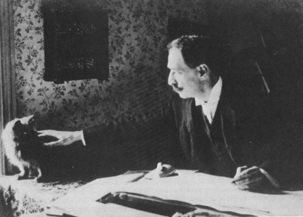 Black and white photograph of Louis Wain at his drawing table in 1890.