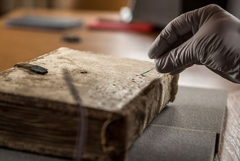 Researchers from BioArCh non-destructively sampling the Gospels of Luke cover.