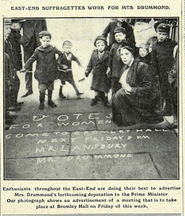 A black and white photograph showing a woman surrounded by children. On the paving stones in front of her is written 'Votes for Women come to Bromley Hall next Friday 8pm.' The headline on the page reads 'East-End Suffragettes work for Mrs Drummond'. The caption below reads 'Enthusiasts throughout the East-End are doing their best to advertise Mrs Drummond's forthcoming deputation to the Prime Minister. Our photograph shows an advertisement of a meeting that is to take place at Bromley Hall on Friday of this week'.