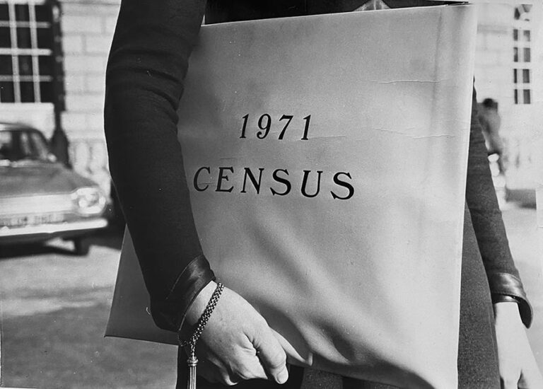 A photograph of someone carrying a satchel with the wording 1971 census.