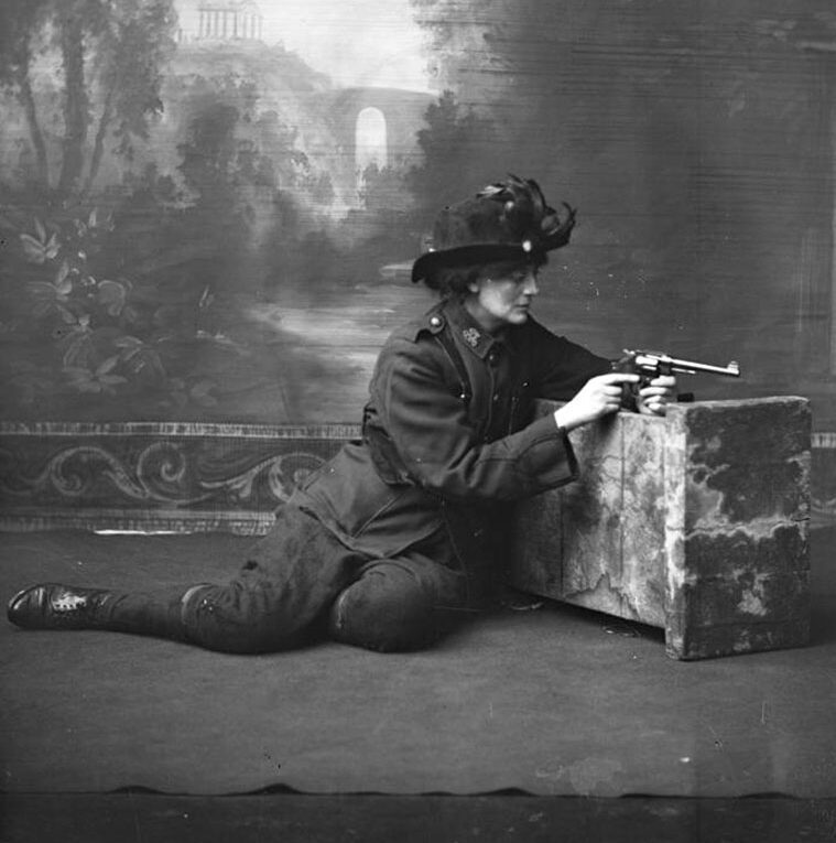 Studio portrait of Constance Markievicz in uniform with a revolver.