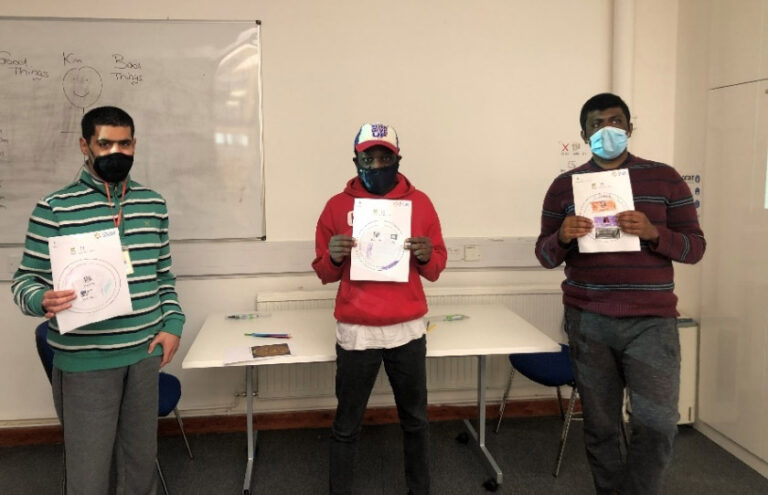 Three of the students from Share community holding up pictures of their completed seals.