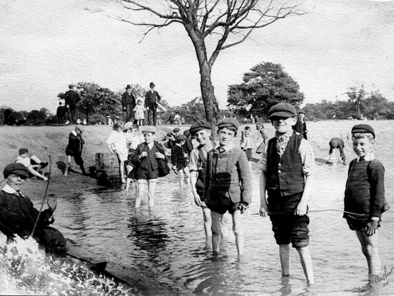 A black and white photograph of a group of boys wading in the pond on Tooting Common, London, taken in 1904.