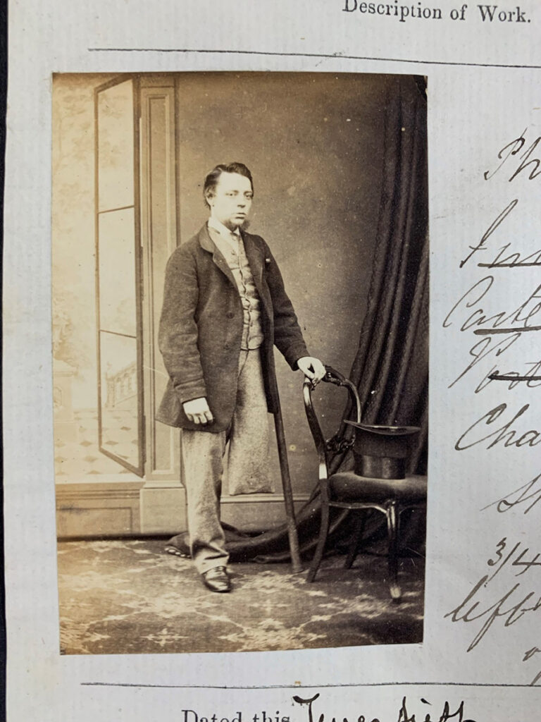 Photograph of Charles Moore, standing, ¾ face, left hand on back of chair'.