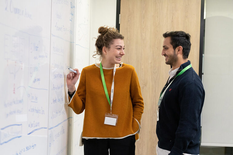 Two of the participants stand in front of a white board.