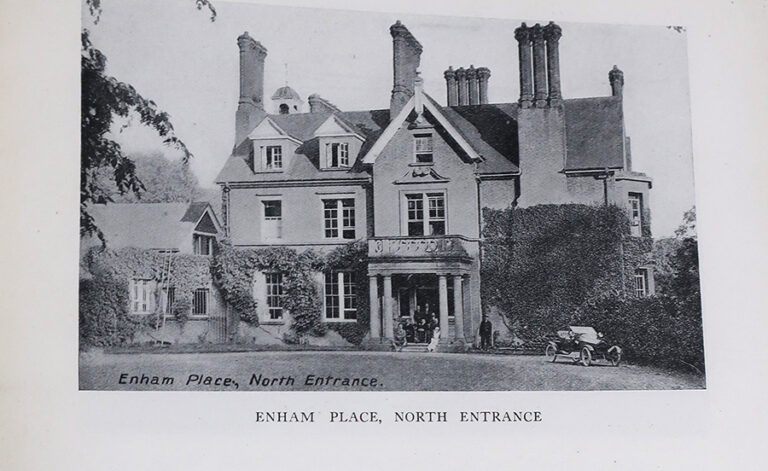 A large three story manor house. A family stands in the doorway, and a motor car is parked on the driveway.