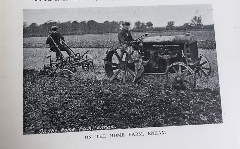 Two men working on the farm, driving a tractor to plough a field.