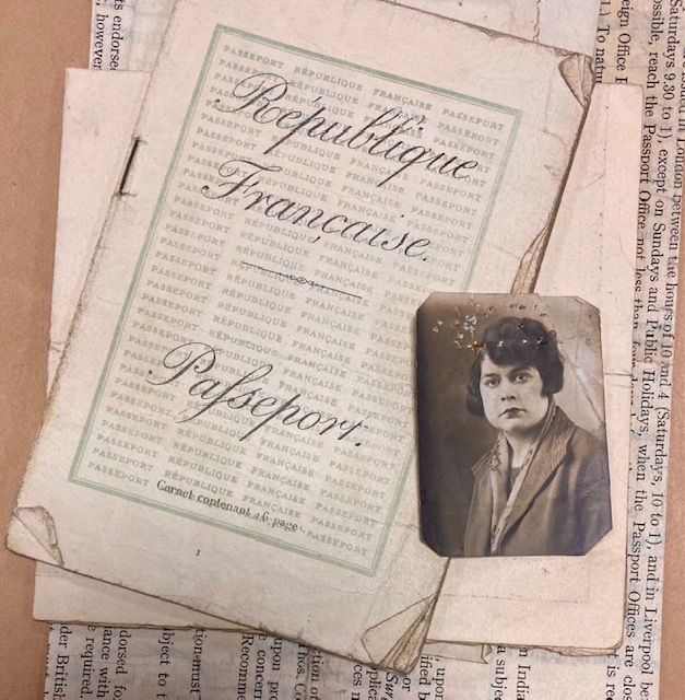 A pile of documents. On top of the pile is a French passport, adjacent to a passport photo of a young woman.