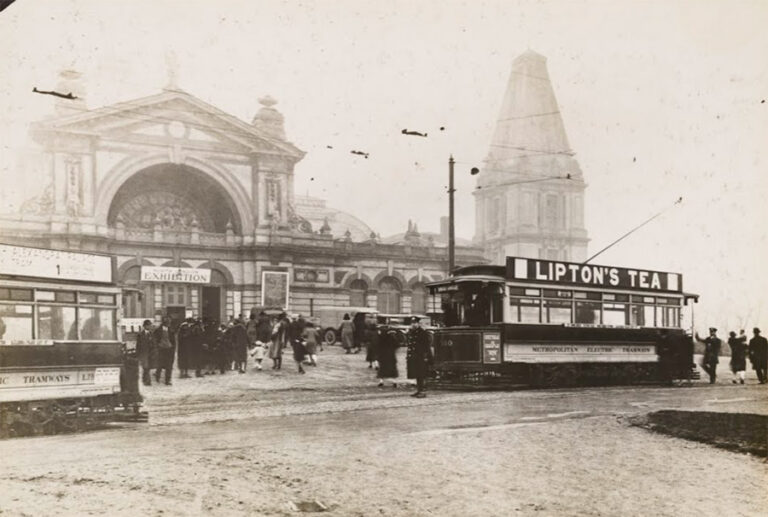 Trams and crowds of passengers outside the front entrance to Alexandra Palace.