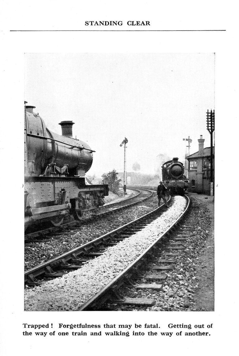 Two steam trains face each other on either side of the tracks, and a railway worker stands in the foreground.