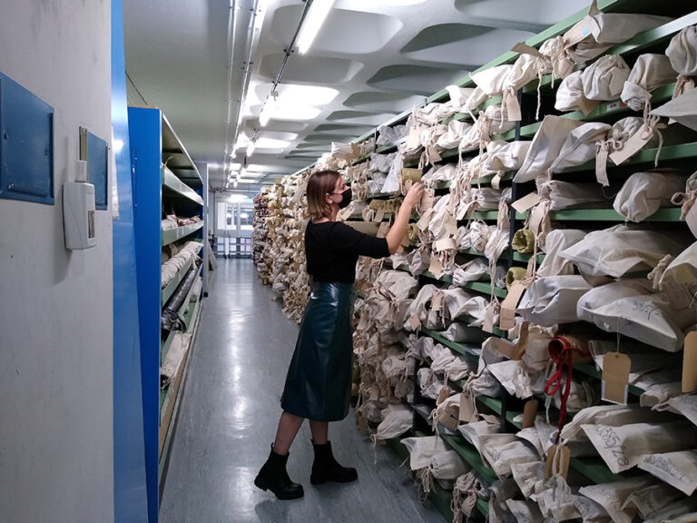 A female archivist looks for material in the well-stocked shelves in an archive.