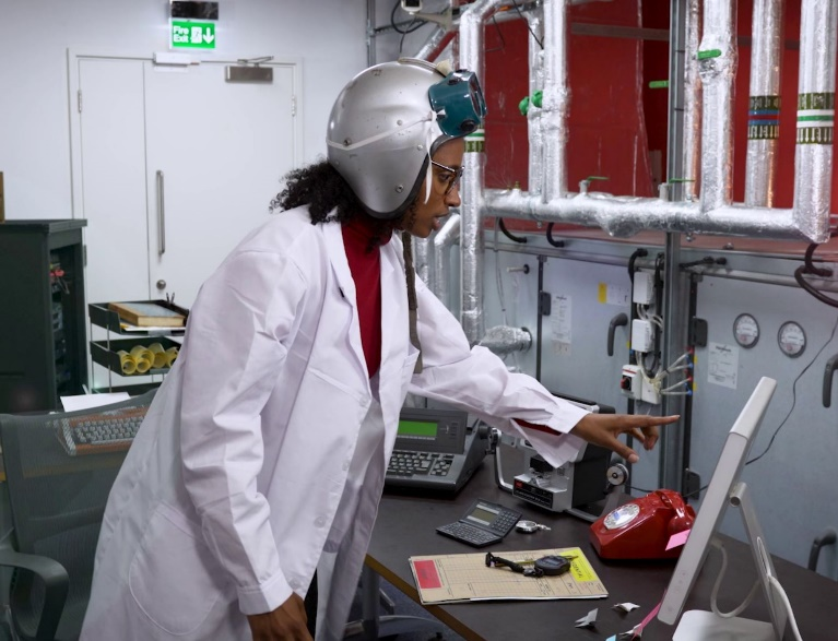 A researcher in a laboratory wearing a silver helmet.