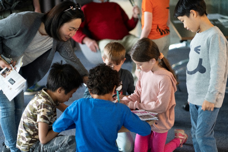 A group of young children sitting around a table drawing pictures.