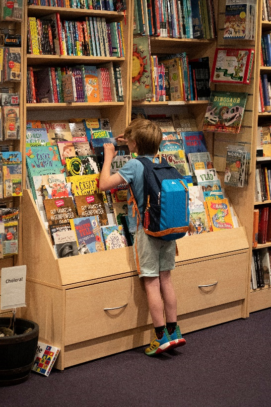 A young child in a bookshop looking closely at a selection of picture books.