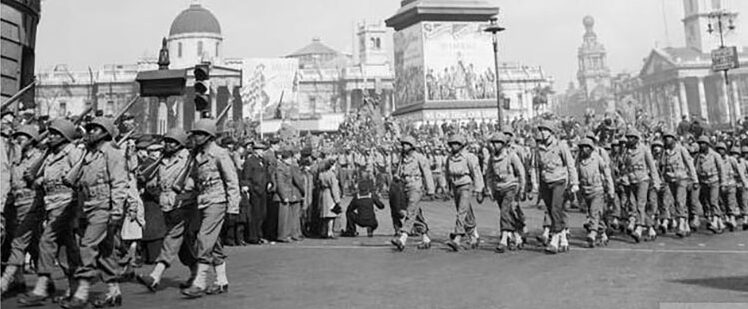 Black American troops in military uniform parade through Trafalgar Square in London.