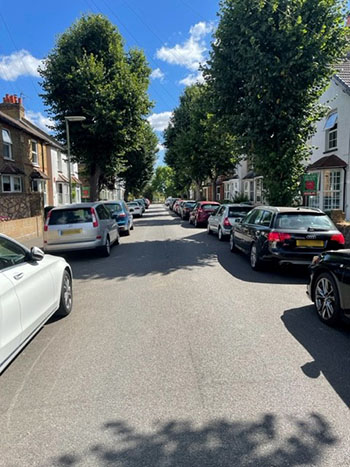 Suburban street with cars parked outside houses.