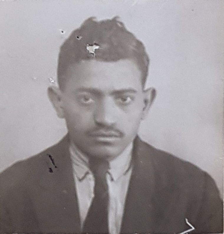 Passport photograph of a young man wearing a suit and tie.