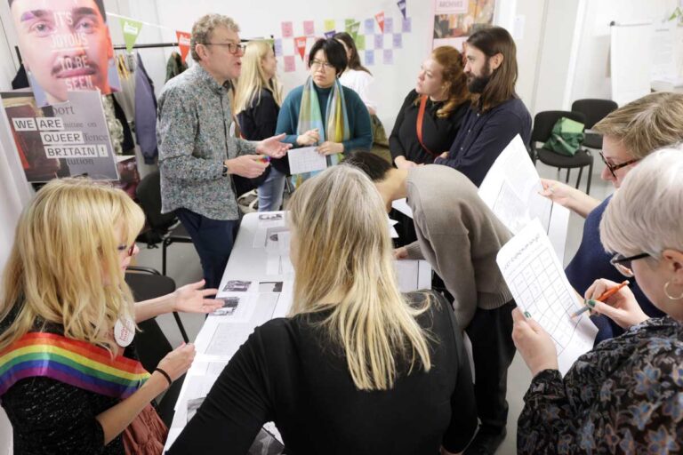 A group of people are having a discussion, while others look at worksheets.