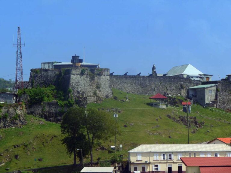 Photo of a stone wall lined with cannons on a hill.