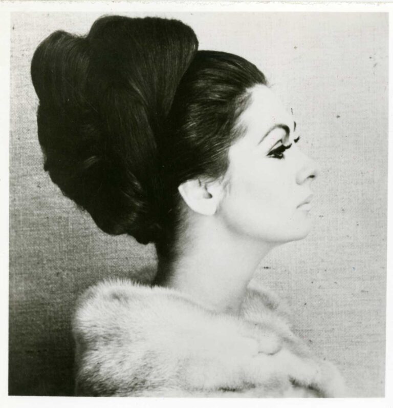 Portrait photo of a women with a beehive haircut, looking to the right.