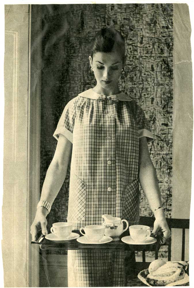 A woman holding a tray with teacups on it.
