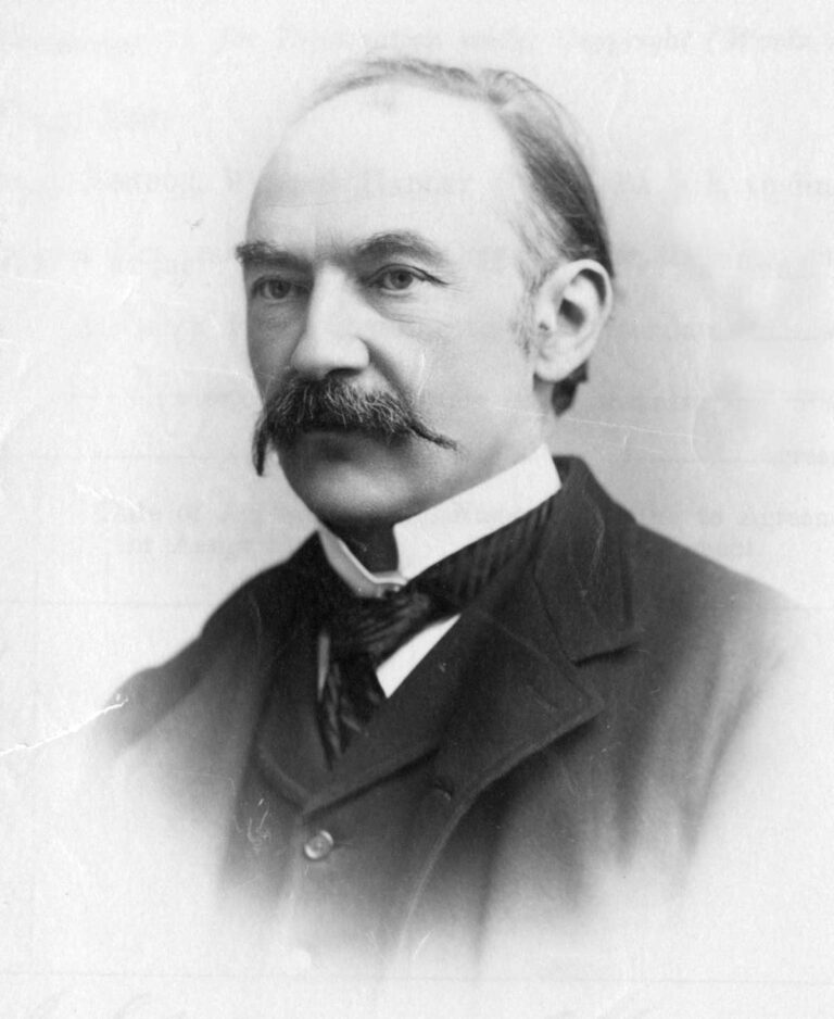 Black and white photo portrait of a man with a receding hairline and a moustache.