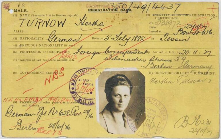 A yellow registration card covered in writing  with a black and white photo of a woman in a light jacket