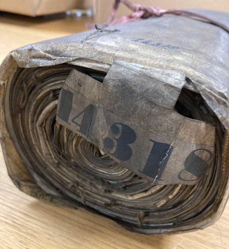 The end of a large rolled up document. It looks very old and dusty and has a big printed label with the number 14138
