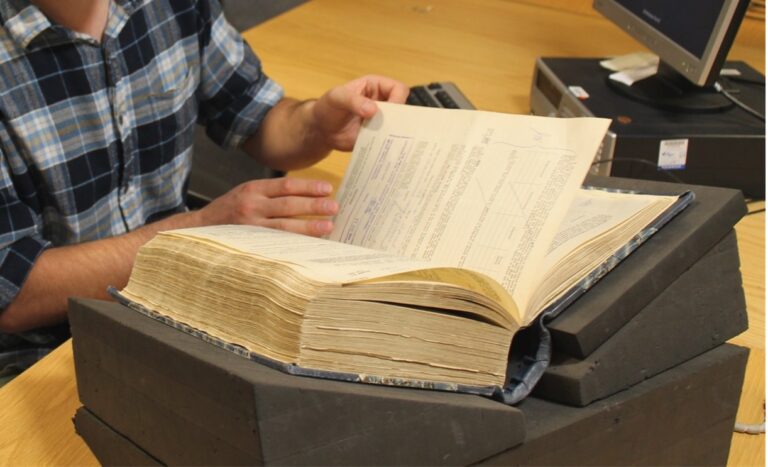 Someone in The National Archives' Reading Room handling a archival book.