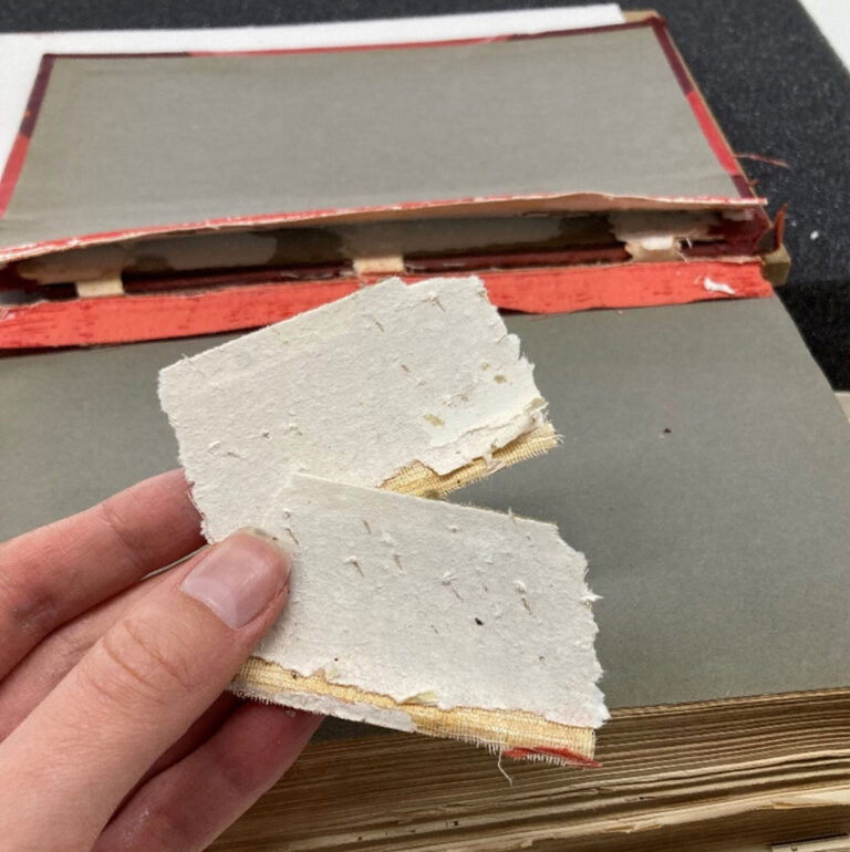 A hand holds two white packets from a book split board.