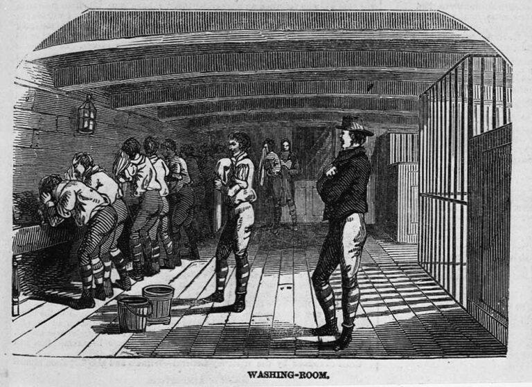 An illustration of a number of men in a room on the lower deck of a ship, they are washing in a communal trough. The men are being observed by guards. 