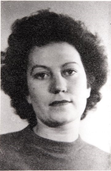 Portrait photo of a woman with thick, dark hair wearing a jumper, with a serious expression.