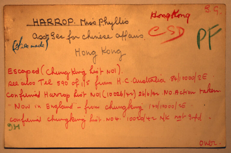 An index card with handwritten notes on it. The notes are written at different times and in different colours: red, black and green. There are dates and the name Harrop written. 