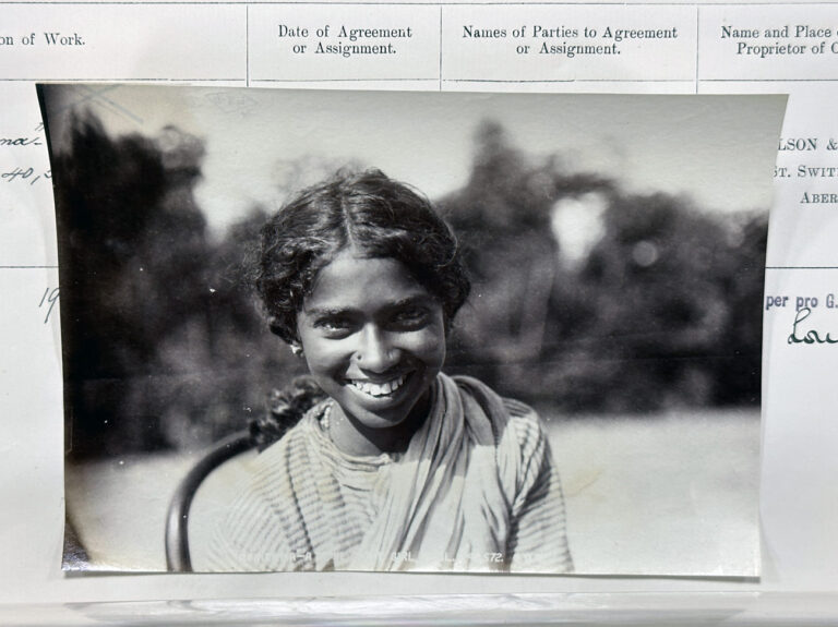 A female smiling in a rural-looking setting. 