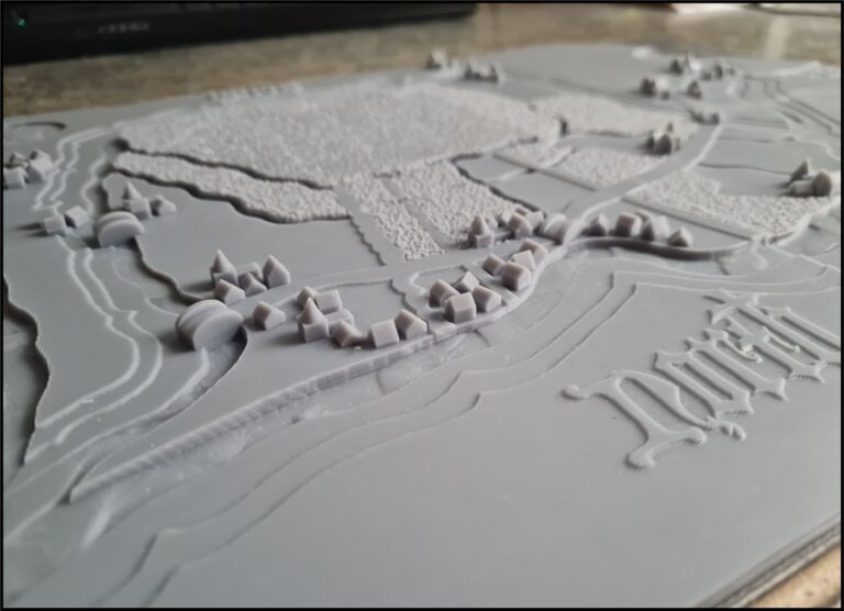 Close-up of a tactile version of a map showing small houses and bridges.